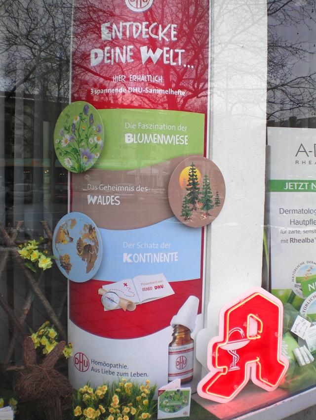 Schaufenster einer Apotheke mit offener Reklame für Quacksalberei -- Homöpathie. Aus Liebe zum Leben.