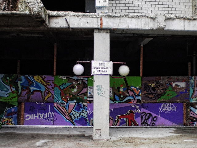 Ein Schild, das mitten in Zerfall und gnadenloser Tristesse des Ihmezentrums steht, mit der Aufschrift 'Bitte Fahrradständer benutzen'.